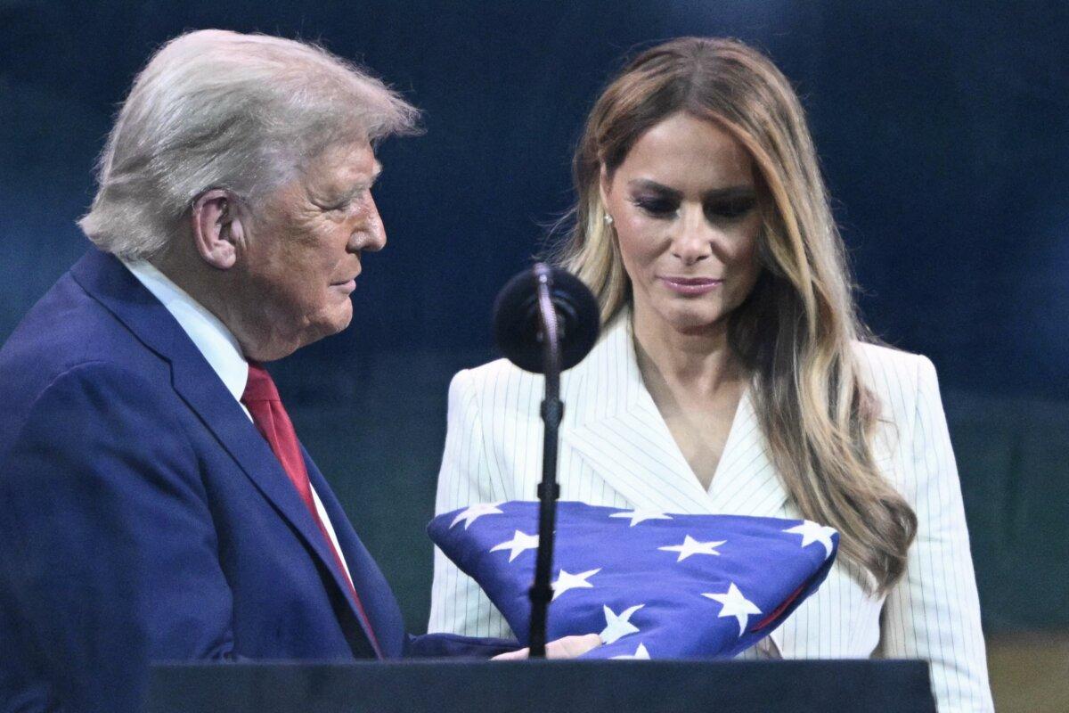 President Donald Trump (L) and First Lady Melania Trump (R) look at a U.S. flag handed to Trump by a member of the Army's Golden Knights during the Army 250th Anniversary Parade in Washington on June 14, 2025. (Mandel NGAN / AFP)