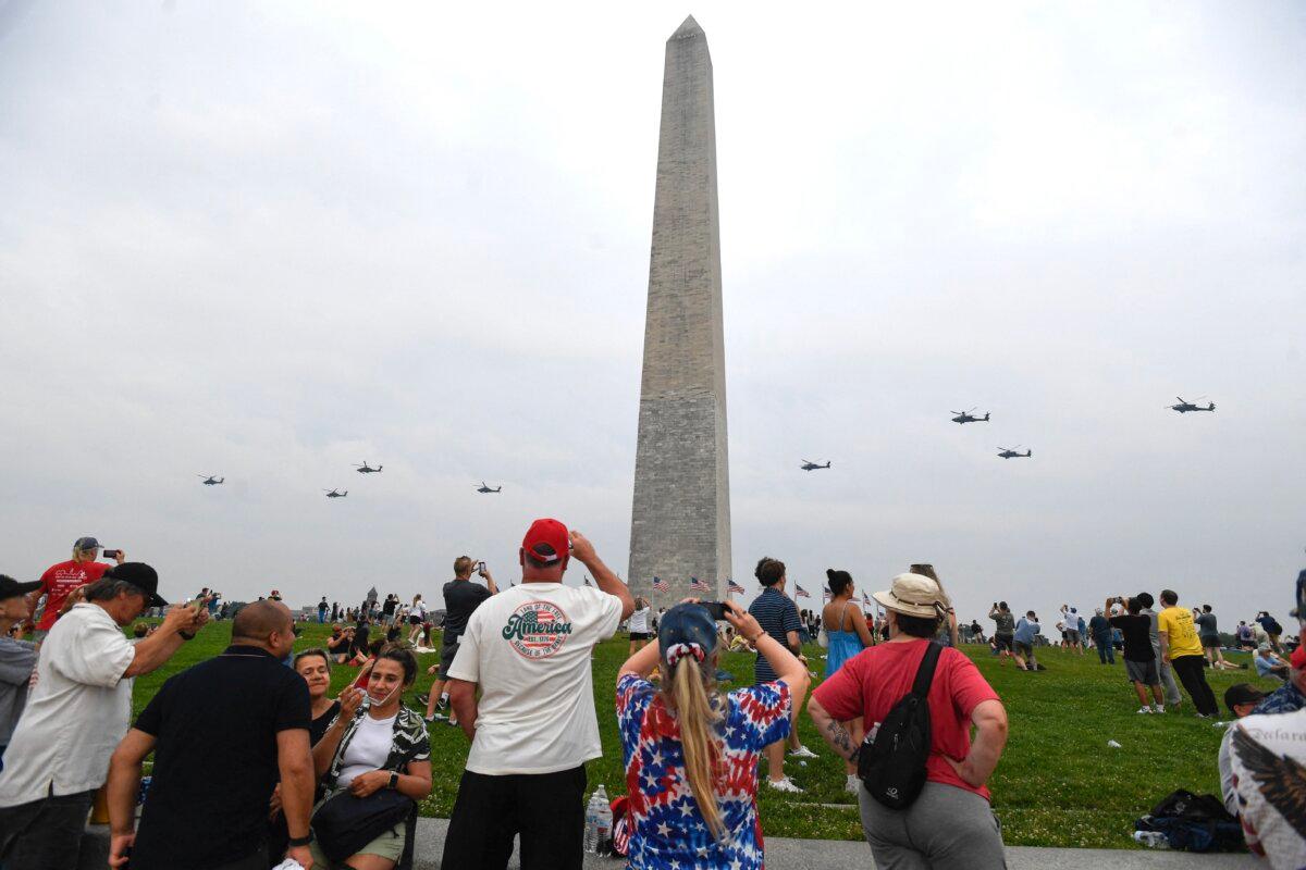 Spectators watch as helicopters do a flyover past the Washington Monument during the Army 250th Anniversary Parade in Washington on June 14, 2025. (Matthew Hatcher / AFP)