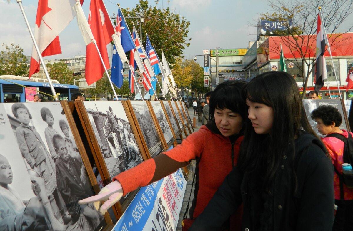 A mother brings her daughter to teach her about the horrors of the June 25, 1950, Korean War through photos in Nov. 12, 2011. (Courtesy of Ahn Jae-chul, president of The World Peace Freedom United)