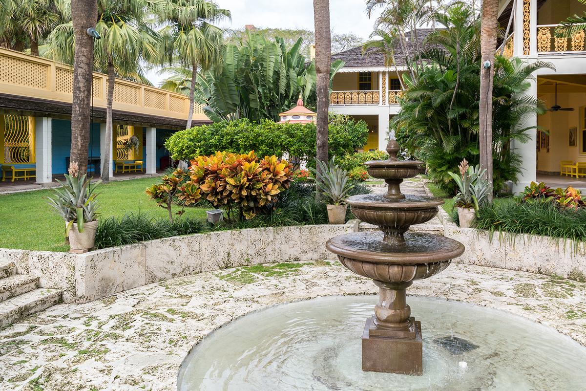 Situated on 35 acres, Bonnet House is surrounded by manicured inner courtyard gardens, with a tiered fountain as a focal point. Coral rock is used in the construction of the walkways through the gardens. Although white and yellow are the dominant colors of the house, cerulean blue brightens the walls of some of the covered porches. (TasfotoNL/Shutterstock)