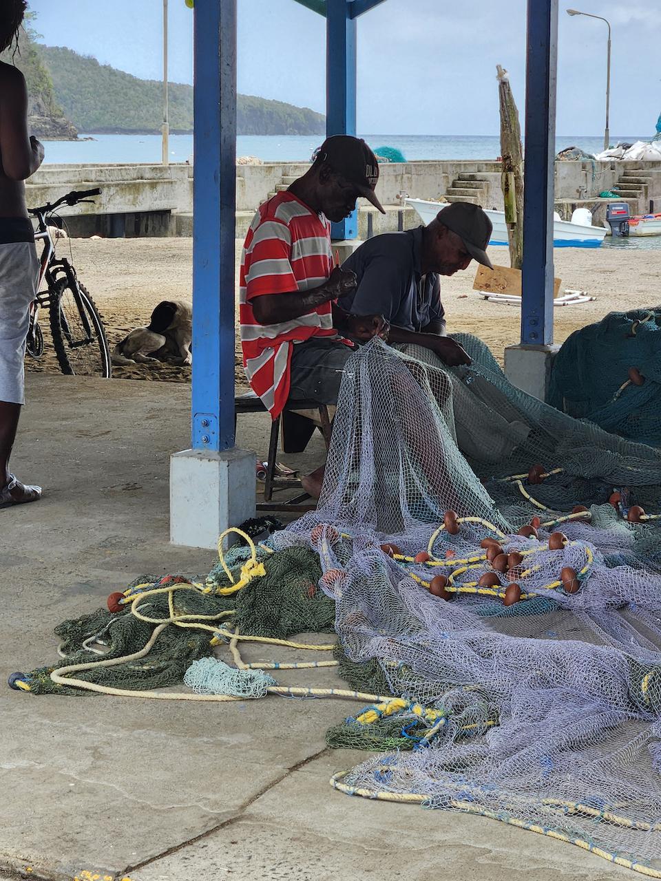 Two fishermen work to repair their nets in St. Lucia's seaside village of Anse La Raye. (Myscha Theriault/TNS)