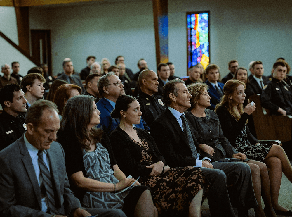 John Bouchart (Dennis Quaid, first row, fourth from left) and his wife Patty (Nancy Travis, to the right of Quaid) at a memorial, in "Sovereign." (Briarcliff Entertainment)