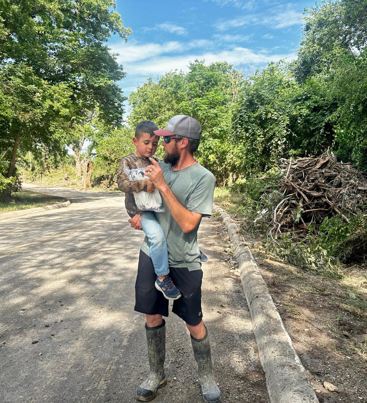 Zachary Clark holds his 5-year-old son while describing the catastrophic flooding along the Guadalupe River near Comfort, Texas, on July 7, 2025. (Darlene McCormick Sanchez/The Epoch Times)