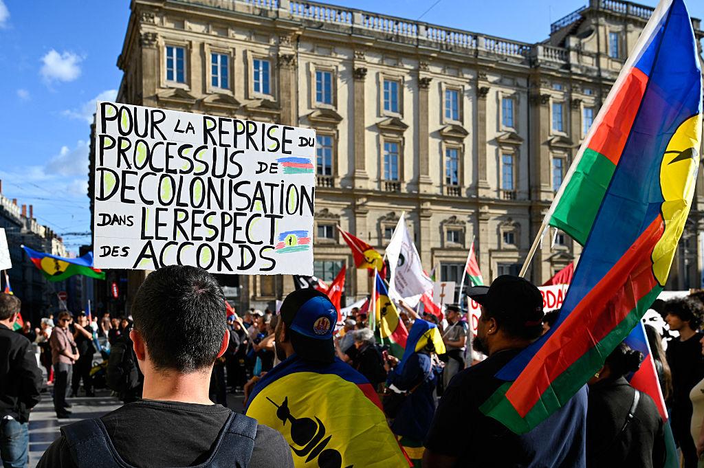 A demonstrator holds a placard during a gathering in support of the New Caledonia Kanaky people in Lyon in France, on May 13, 2025. (MATTHIEU DELATY/Hans Lucas/AFP via Getty Images)