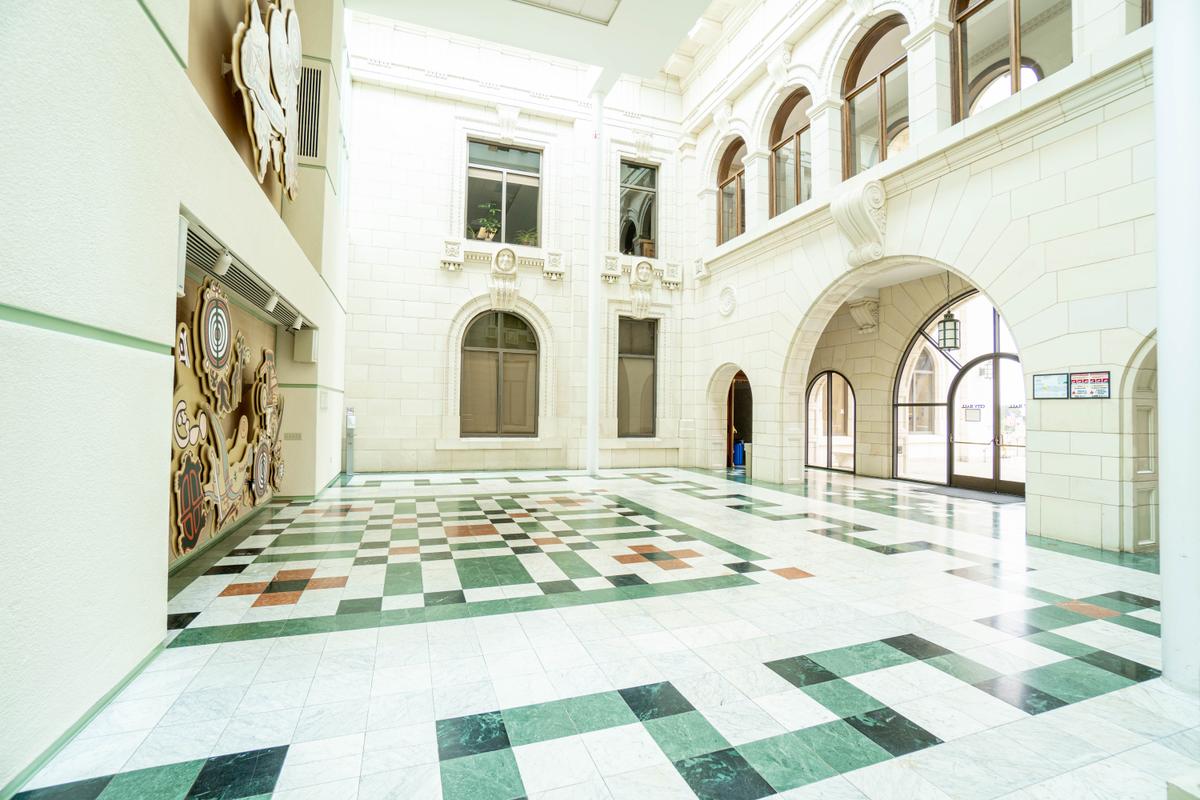 The entryway atrium hall features <a href="https://www.cityofventura.ca.gov/DocumentCenter/View/7210/Historic-City-Hall-Brochure?bidId=" target="_blank" rel="nofollow noopener">1,370</a> square feet of mosaic marble in the geometric flooring, which complements the white-glazed terra cotta block walls. A classic keystone corbel is the embellishment over the arched entrances. Friars’ heads carved in terra cotta are a historical reminder that Ventura was one of nine original mission towns founded by a Catholic priest and Franciscan friars. (City of Ventura)