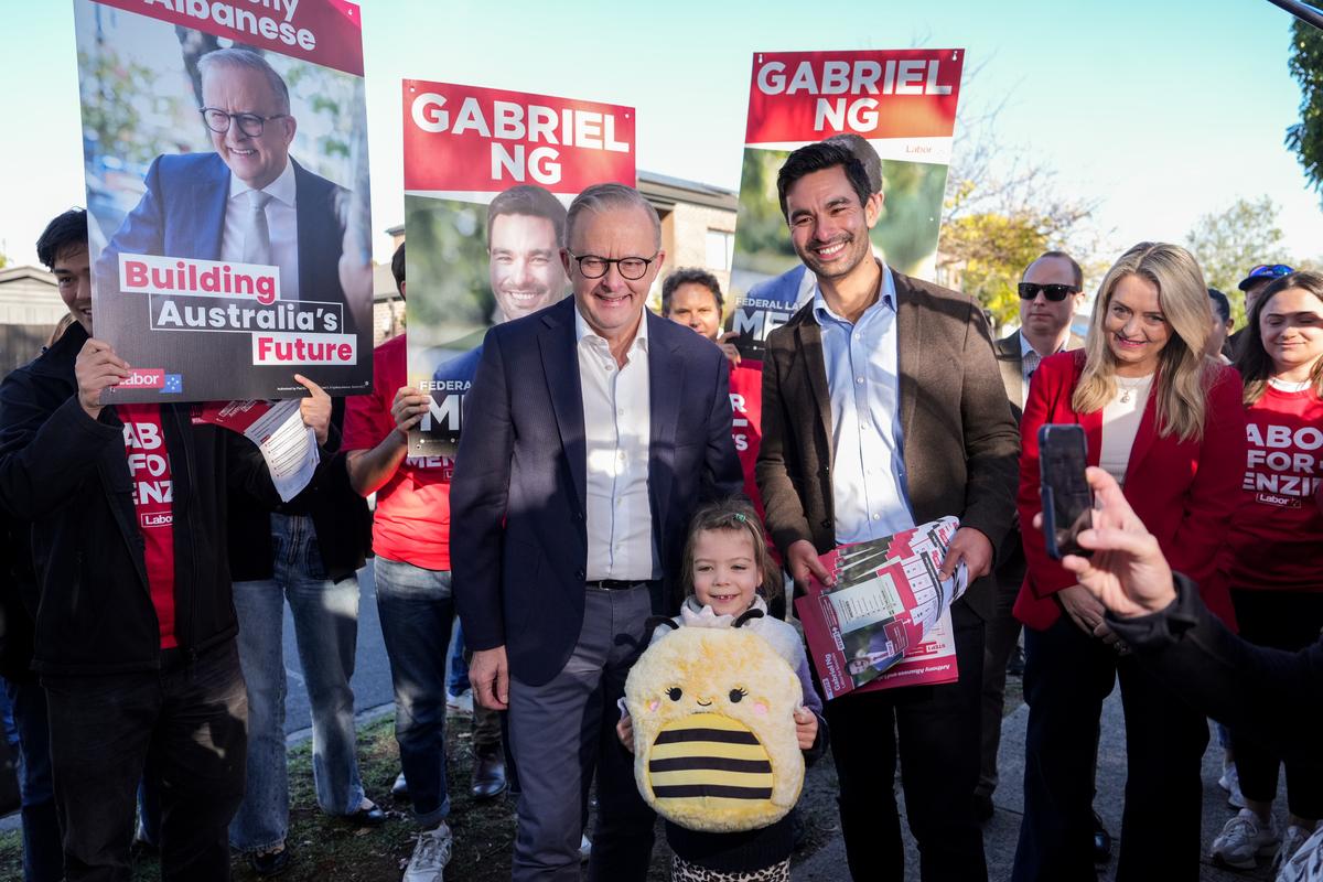 Prime Minister Anthony Albanese and Labor's Gabriel Ng pose for a photo with a child holding a bumblebee plushie at a polling station in Box Hill North in Melbourne, Australia on May 3, 2025. (Asanka Ratnayake/Getty Images)