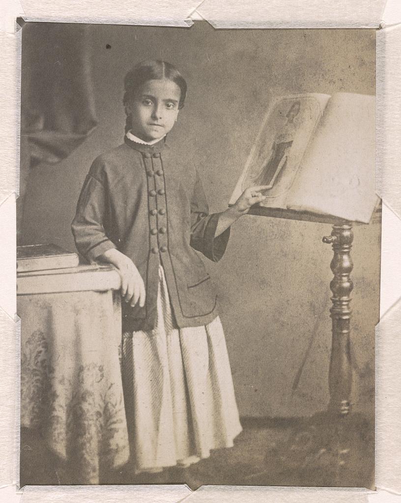 Adelina Patti, pointing at a portrait of Jenny Lind printed on sheet music. Library of Congress. (Public Domain)