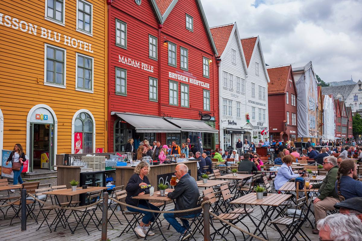 Bryggen's Hanseatic heritage commercial buildings line the east side of the Vagen Harbor, providing a homey backdrop for patrons enjoying the outdoor bar. (JWCohen/Shutterstock)
