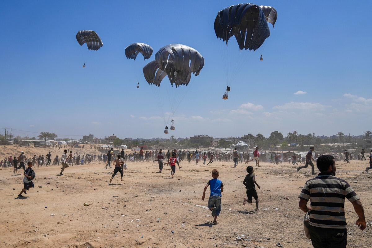 Palestinians rush to collect humanitarian aid airdropped by parachutes into Zawaida in the central Gaza Strip, on Aug. 4, 2025. (Abdel Kareem Hana/AP Photo)