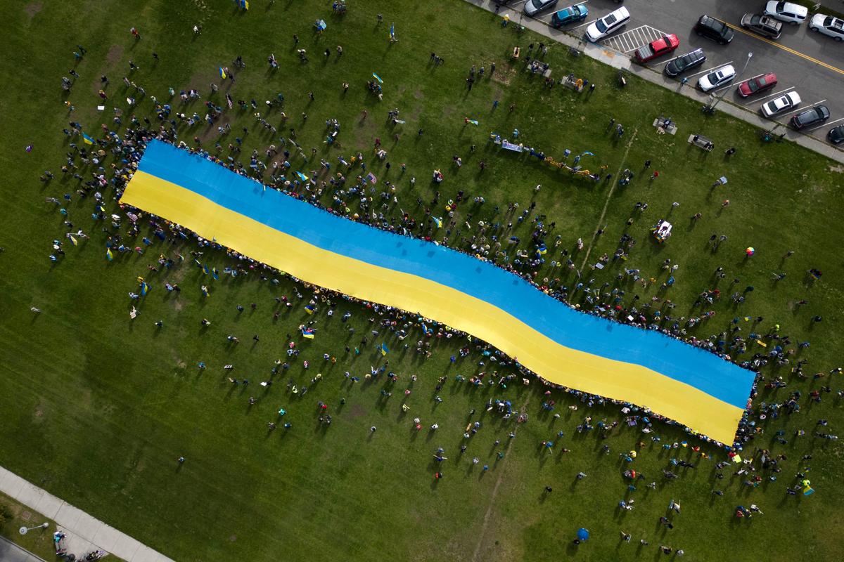 This aerial view shows protesters holding a giant Ukrainian flag in Anchorage, Alaska, on August 15, 2025 during a US-Russia summit at nearby Joint Base Elmendorf-Richardson. (Daphne Lemelin/AFP via Getty Images)