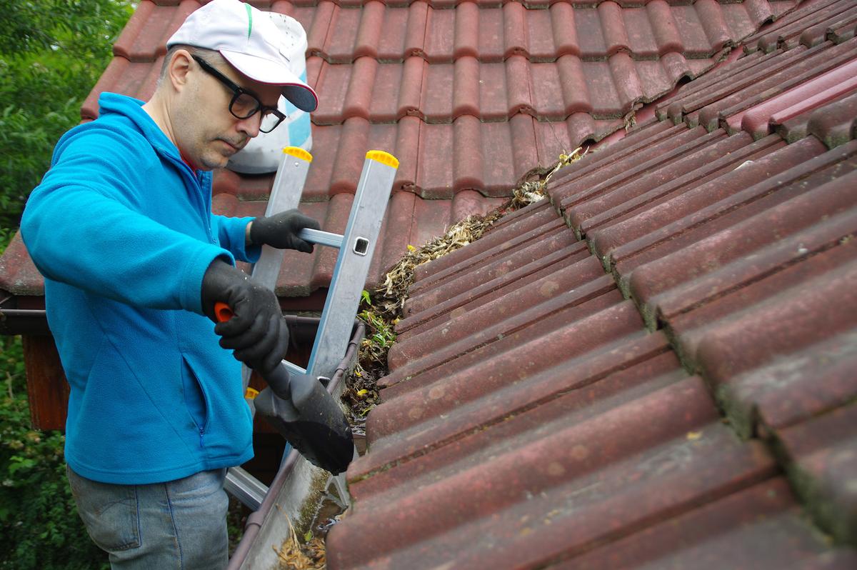 Cleaning gutters in the fall prevents clogs and ensures the gutter system can handle heavy winter precipitation. (Arkadiusz Warguła/Getty Images)