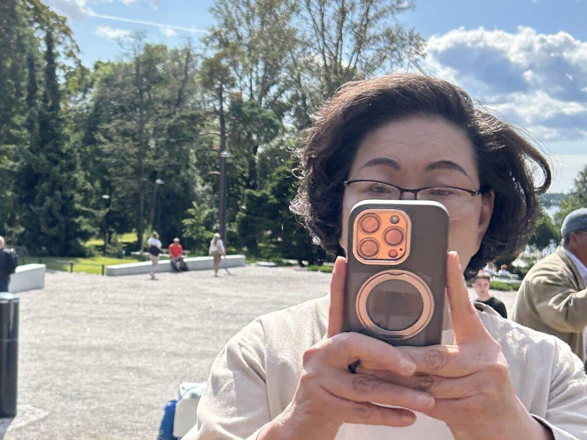 Regina Leung Tong Ching-yee, wife of Leung Chun-ying, photographs Falun Gong practitioners at the meditation site in Helsinki on Aug. 13, 2025. (Courtesy of Falun Dafa Information Center)
