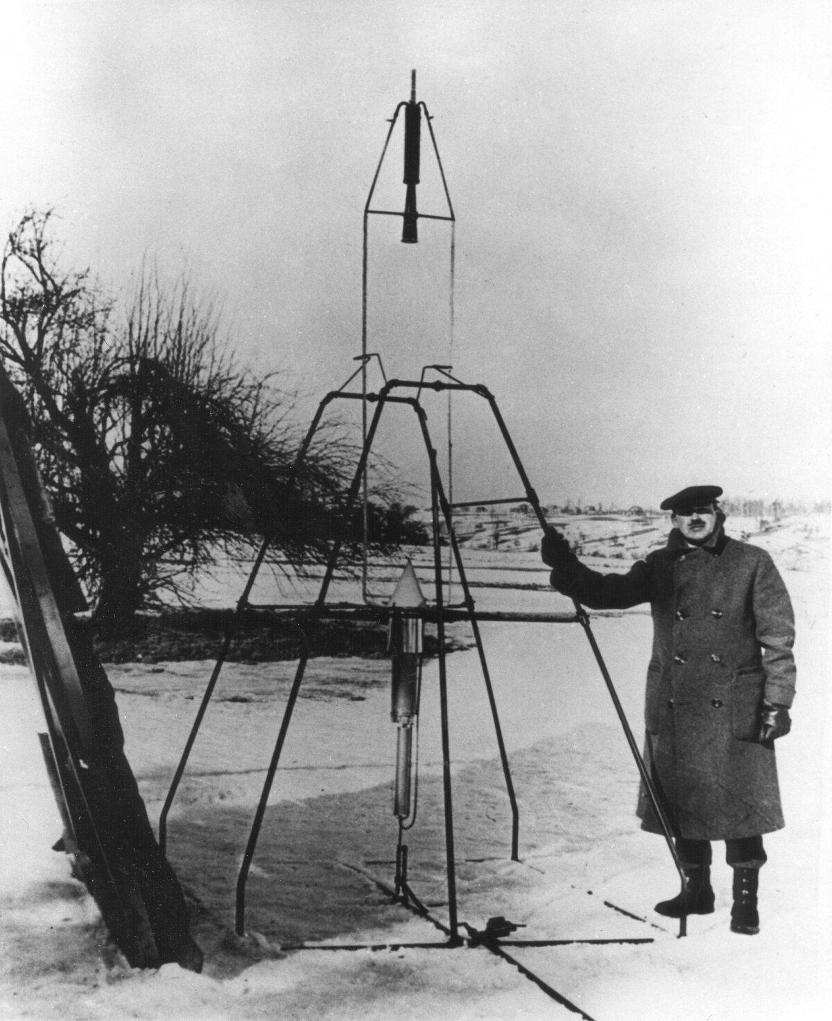 Robert Goddard, bundled against the cold weather of March 16, 1926, holds the launching frame of his most notable invention—the first liquid-fueled rocket. Esther C. Goddard. (Public Domain)