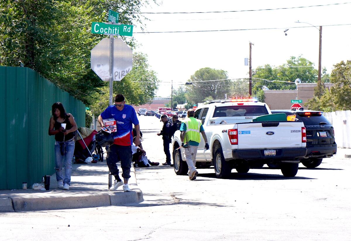 Police officers disperse a group of homeless people sitting along a fence near Central Avenue in Albuquerque, N.M., on Sept. 3, 2025. (Allan Stein/The Epoch Times)