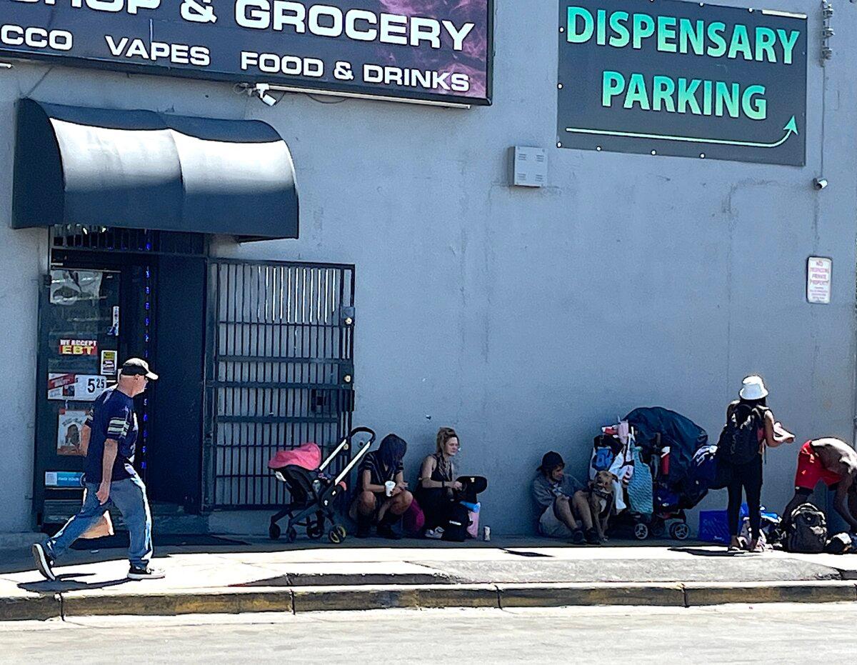 A group of people in the shade of a building off Central Avenue in the International District of Albuquerque, N.M., on Sept. 3, 2025. (Allan Stein/The Epoch Times)