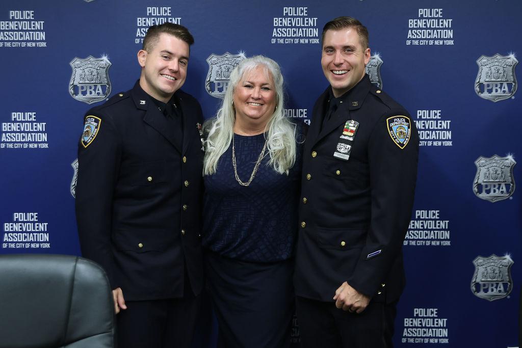 Former NYPD Officer Kathy Vigiano (C) poses with her sons, James Vigiano (L) and Joseph Vigiano Jr., both NYPD officers, during the unveiling of the 9/11 Memorial Wall at the Police Benevolent Association of the City of New York on Sept. 7, 2021. Kathy's husband, Detective Joseph Vigiano, was killed in the Sept. 11, 2001 attack. (Chip Somodevilla/Getty Images)