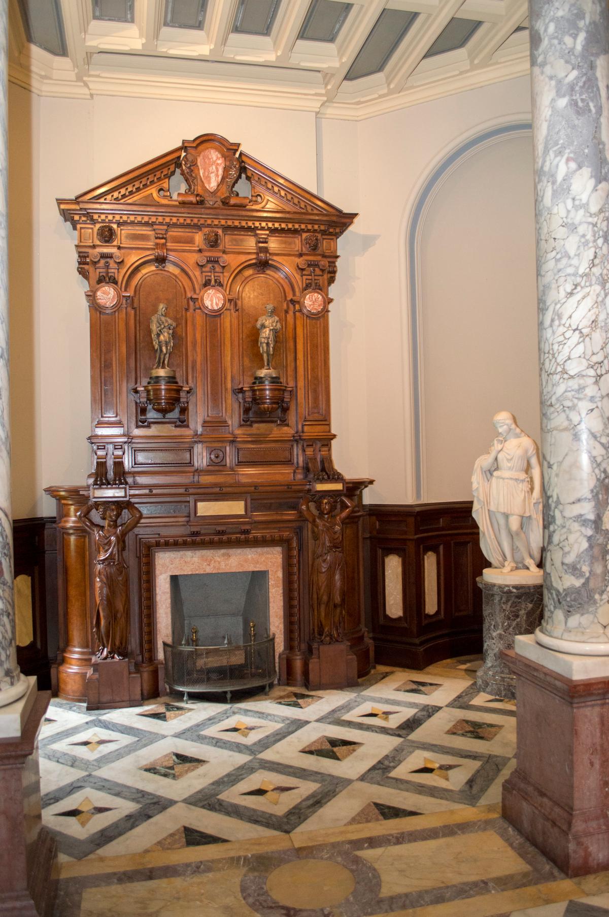 The hall features plaster walls and ceilings, four Florentine marble columns on bases of <a href="https://tile.loc.gov/storage-services/master/pnp/habshaer/ct/ct0000/ct0097/data/ct0097data.pdf" target="_blank" rel="nofollow noopener">porphyry</a> containing feldspar crystals, star-patterned marble flooring, and a carved, black walnut mantel with a marble fireplace. “The Wept of Wish-ton-Wish,” a <a href="https://artgallery.yale.edu/collections/objects/443" target="_blank" rel="nofollow noopener">statue</a> by Joseph Mozier (1812–1870), which was carved to portray the heroine in James Fenimore Cooper’s tale, stands in one of the corner niches. (Lockwood-Mathews Mansion Museum)