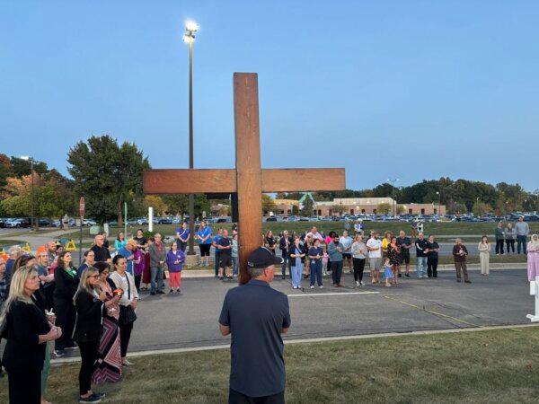 Dan Beazley, who handcrafted a 10-foot, 65-pound cedar cross and takes it to events nationwide where tragedies have occurred, holds the cross at a Sept. 30 vigil for victims of a church shooting in Grand Blanc, Mich. (Jeff Louderback/The Epoch Times)