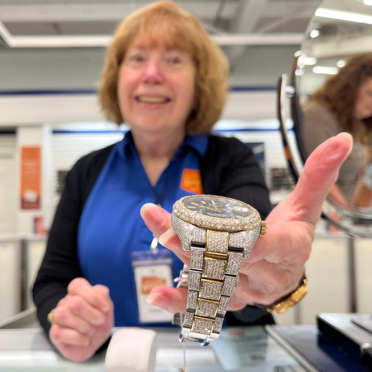 Unclaimed Baggage sales clerk Cathy Pierce holds a diamond-studded Rolex watch valued at $30,000 on Oct. 8, 2025. (Allan Stein/The Epoch Times)