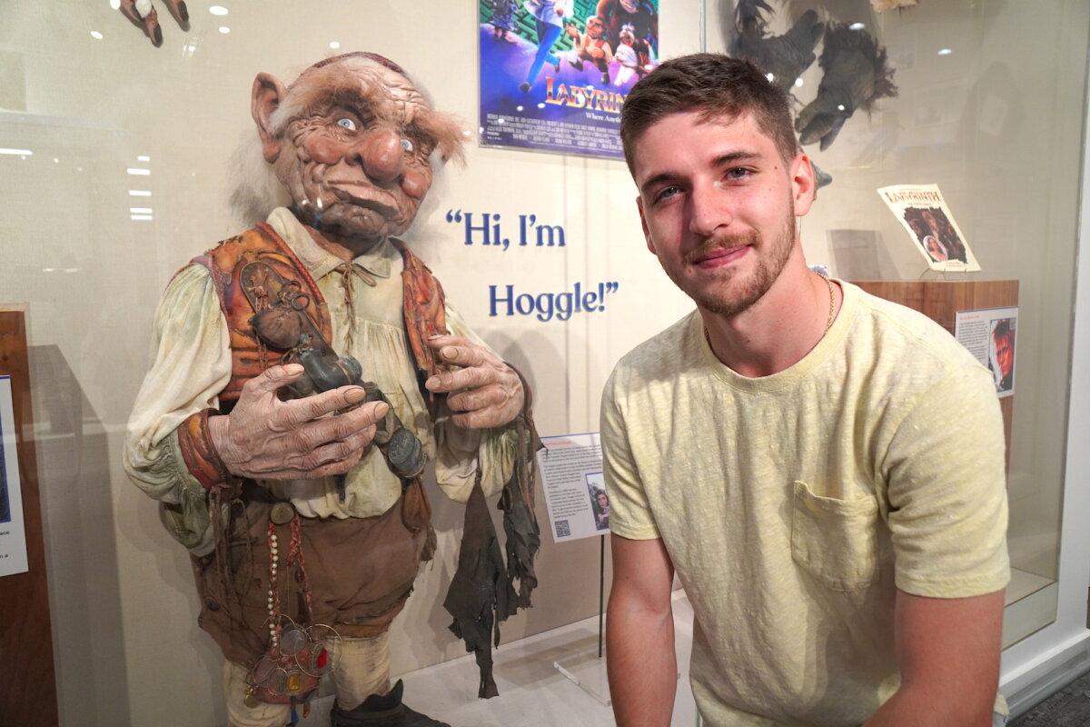 Seth Partlew from Athens, Ga., kneels in front of Hoggle, a puppet from the movie "Labyrinth" starring David Bowie, on Oct. 8, 2025. (Allan Stein/The Epoch Times)
