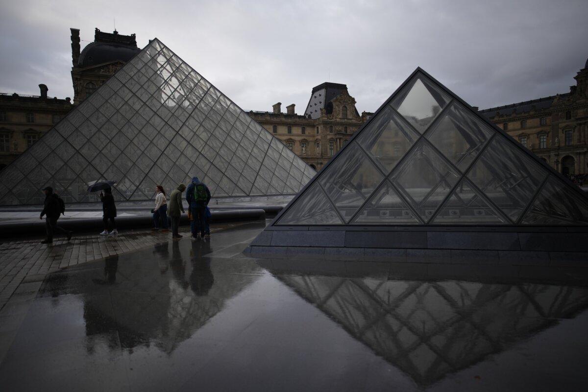 People tour the courtyard of the Louvre Museum in the rain in Paris, on Oct. 27, 2025. (Christophe Ena /AP Photo)