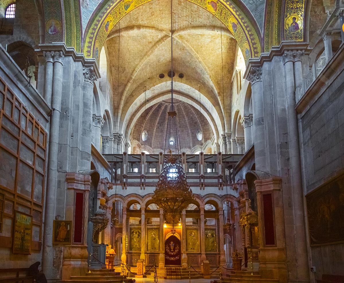 The Greek Orthodox Church controls the Katholikon, the space in front of the Edicule. At the Katholikon's rear is the iconostasis, a partition of icons dividing the altar from the nave featuring red marble arches and columns. Behind the iconostasis is the extant ribbed-vaulted, Crusader-era apse. In the 1960s, excavations beneath the Katholikon’s floor revealed the apse from Constantine’s original building near this spot. (Natalia Tretiakova/Shutterstock)