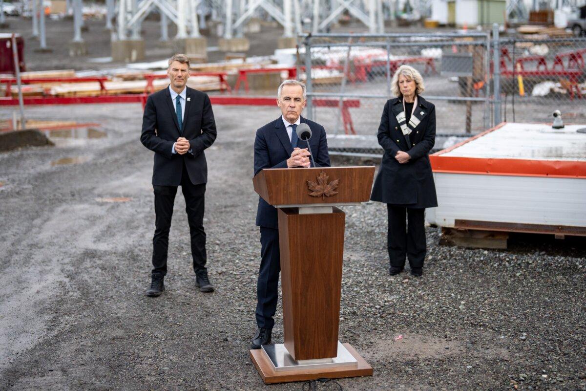 Prime Minister Mark Carney speaks as Chief Executive Officer of the federal Major Projects Office Dawn Farrell and Minister of Housing and Infrastructure Gregor Robertson listen during a major projects announcement in Terrace, B.C., on Nov. 13, 2025. (The Canadian Press/Ethan Cairns)