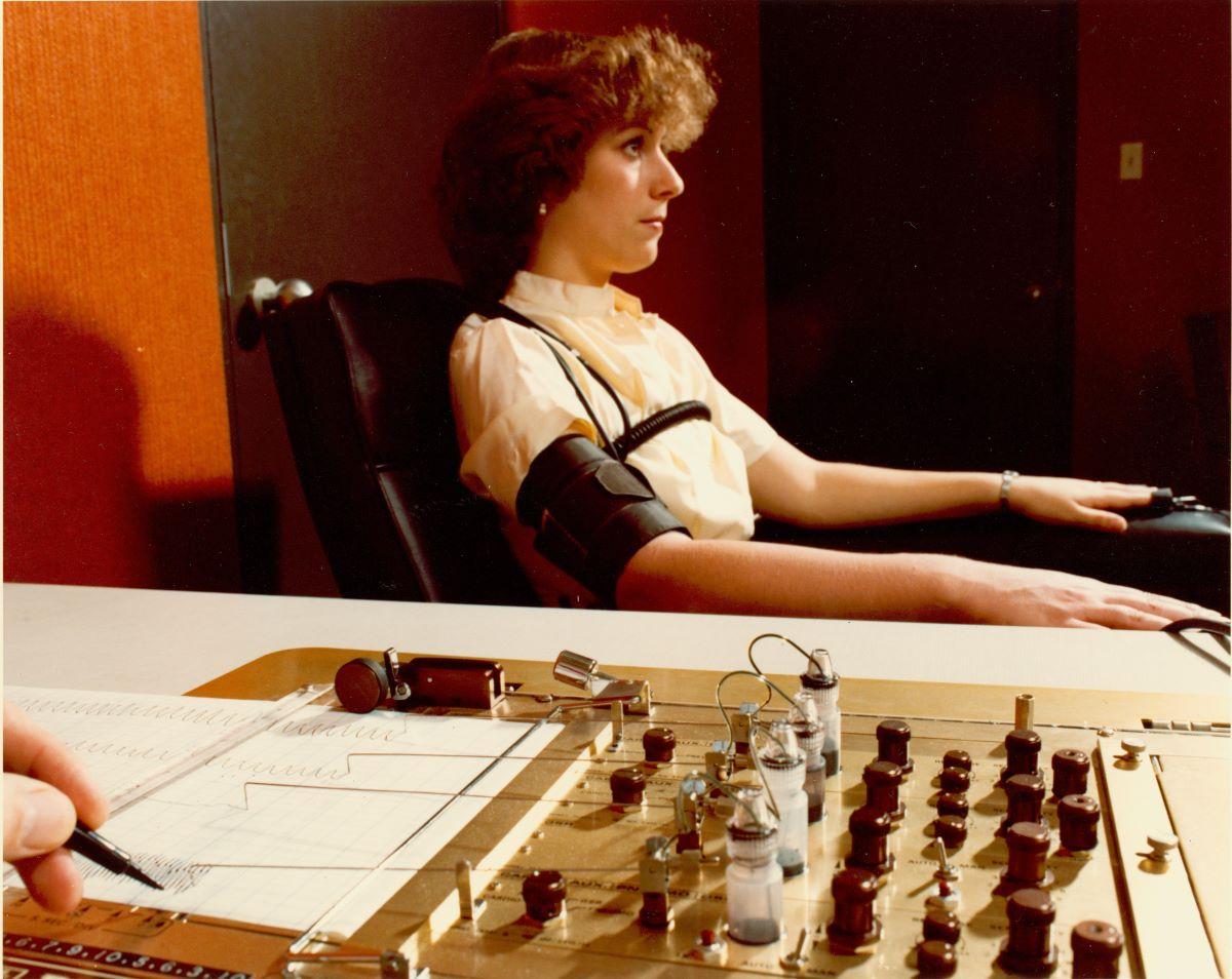 Demonstrating the administration of the polygraph, the polygrapher making notes on the readouts, circa 1970s. (Public Domain)