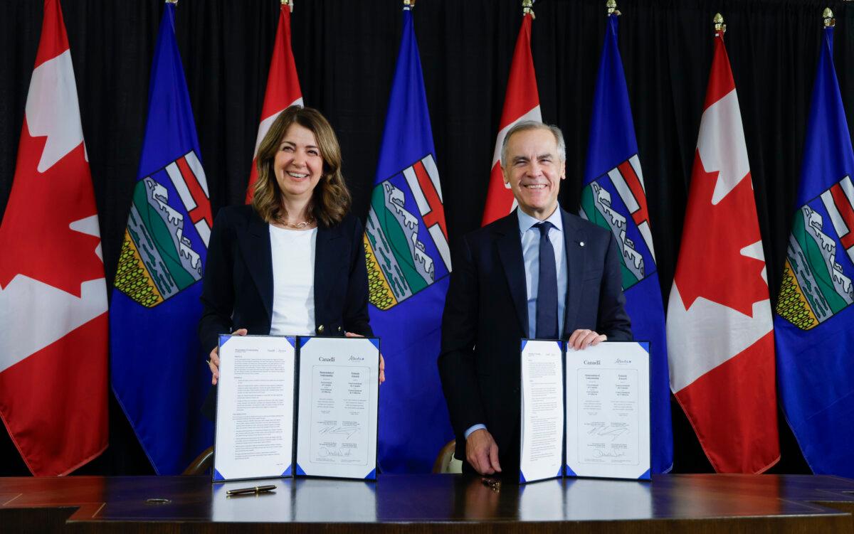 Prime Minister Mark Carney signs an MOU with Alberta Premier Danielle Smith in Calgary on Nov. 27, 2025. (Jeff McIntosh/The Canadian Press)