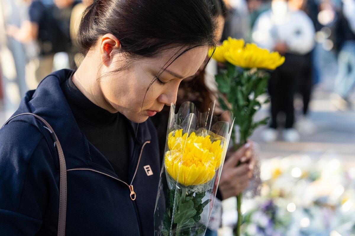 People hold flowers near the site to mourn the victims of the fire at Wang Fuk Court, a residential estate in the Tai Po district of Hong Kong's New Territories, on Nov. 29, 2025. (Chan Long Hei/AP)
