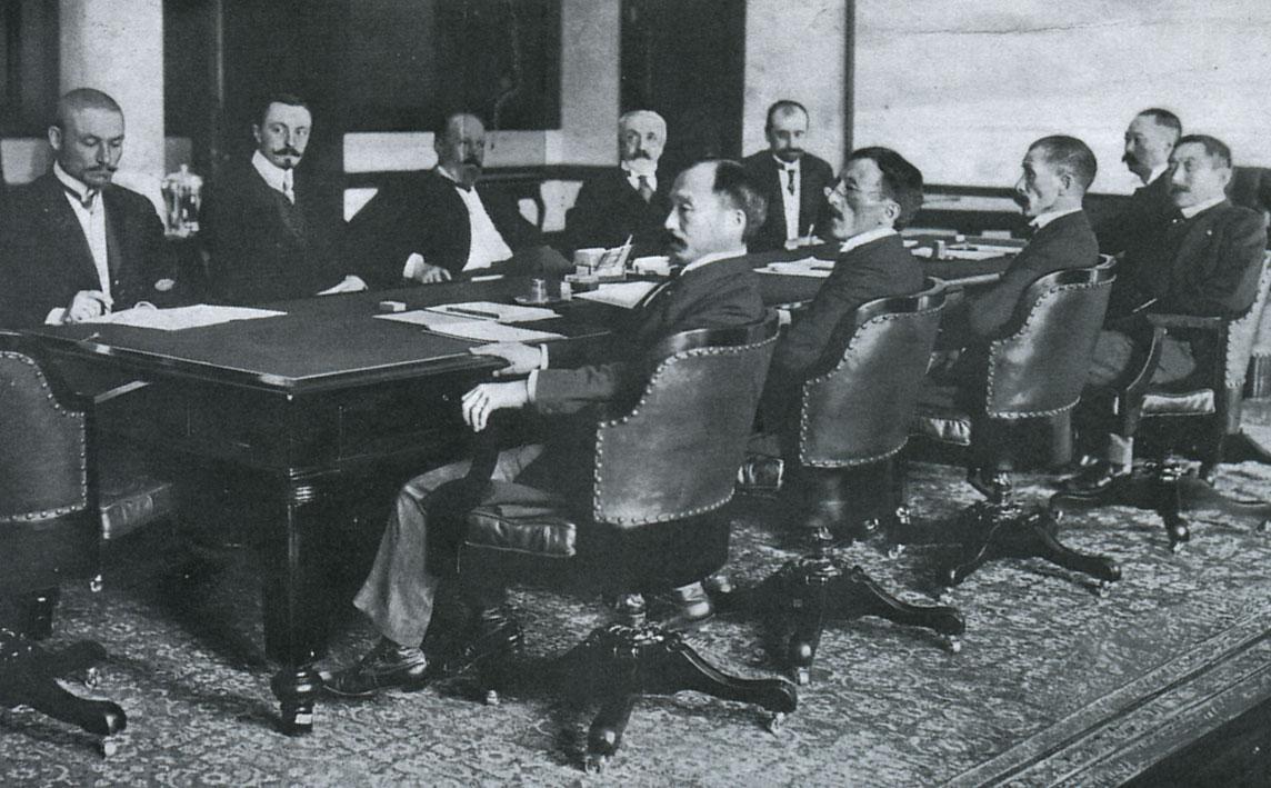 Negotiating the Treaty of Portsmouth (1905). The Russians are at the far side of the table and the Japanese at the near side. The large conference table is today preserved at the Museum Meiji-mura in Inuyama, Aichi Prefecture, Japan. (Public Domain)