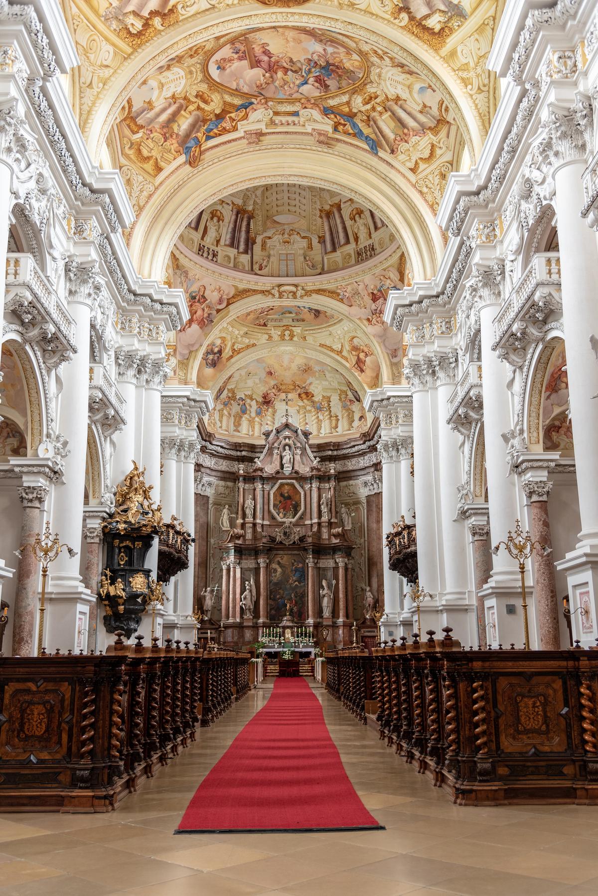 In 1999, the monastery’s abbey church was designated as a minor basilica for its extraordinary architecture and design. White-columned pedestals, protruding entablatures, and balconies appear to elevate and support a series of impressive vaulted domes that lead to the sanctuary area. Painstakingly intricate moldings and carvings appear to embellish every inch of the abbey church, except the ceiling. Fresco paintings richly fill the space inside the vaulted domes. Hand-carved and spiraled wood designs, topped with finials, embellish the nave, or seating area, for worshippers. The nave’s alcoves sport arched openings supported by marble columns. Gilded and marble statues are aplenty in the abbey church as well. (Redfox1980/Shutterstock)