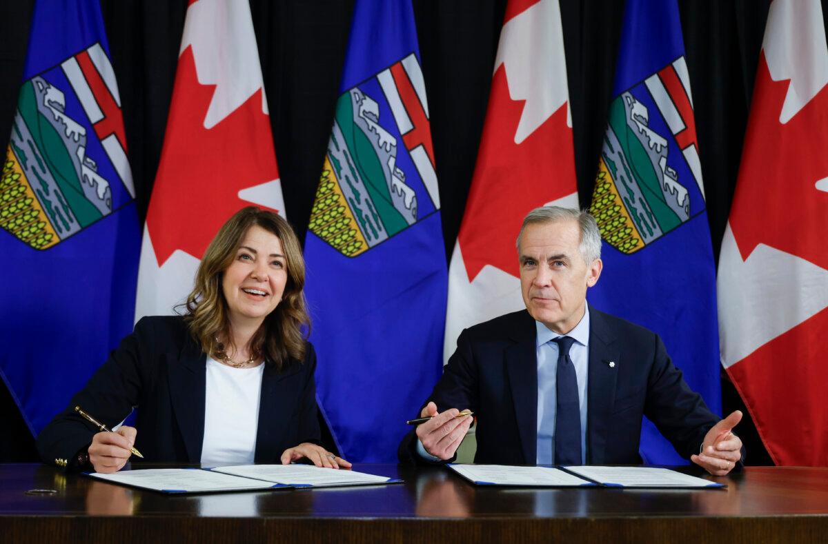 Prime Minister Mark Carney signs an MOU with Alberta Premier Danielle Smith in Calgary on Nov. 27, 2025. (The Canadian Press/Jeff McIntosh)