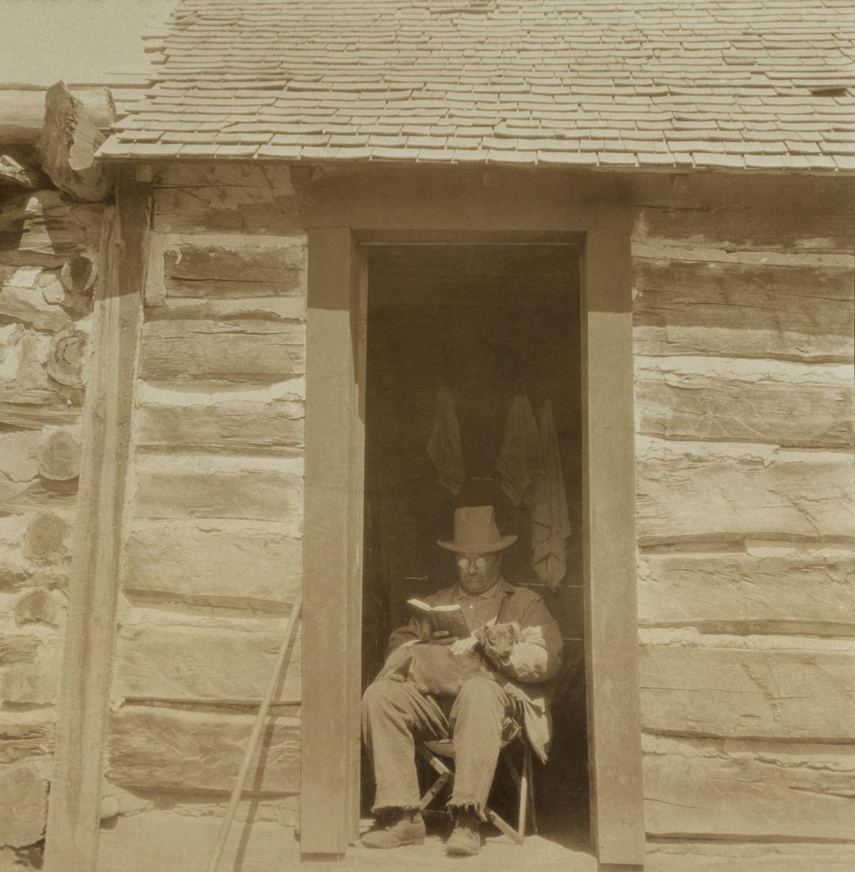 President Theodore Roosevelt reading in the doorway of the West Divide Creek Ranch House in Silt, Colo., circa 1905. On his lap is his hunting dog, Skip. (Everett Collection/Shutterstock)