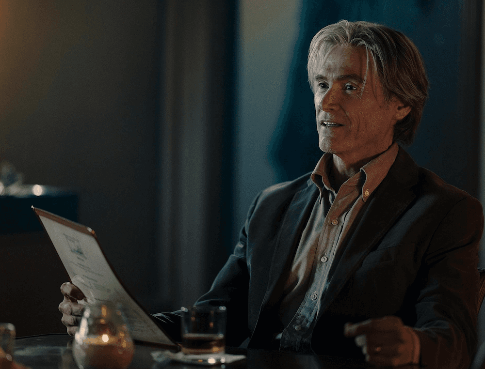 Timothy (Billy Crudup) reads a menu using method acting, in "Jay Kelly." (Netflix)