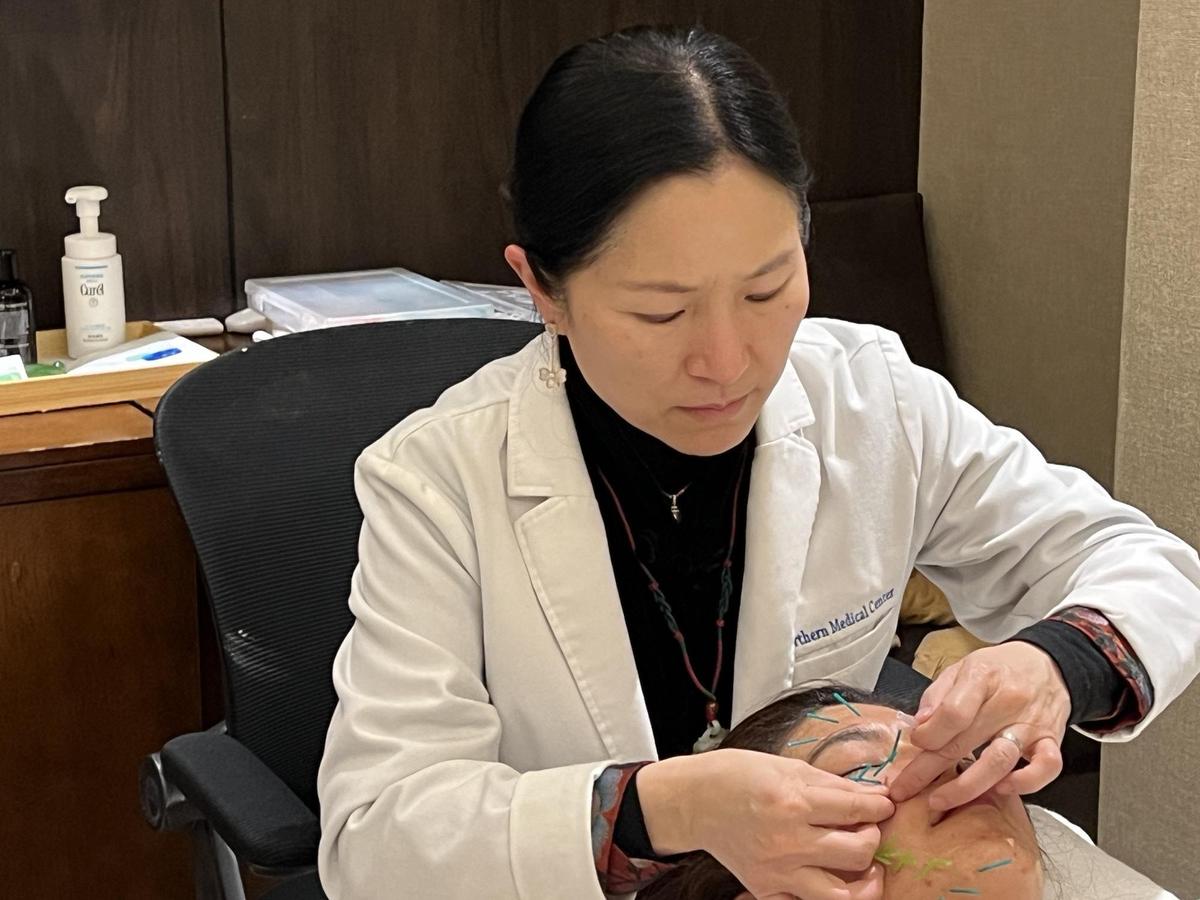 Serene Feng performing facial acupuncture on a patient. (Fenni Zhao/The Epoch Times)