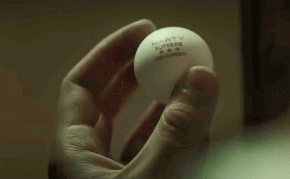 Marty Mauser (Timothée Chalamet) holds a ball made special for him after having sweet-talked a ping pong ball designer in "Marty Supreme." (A24)