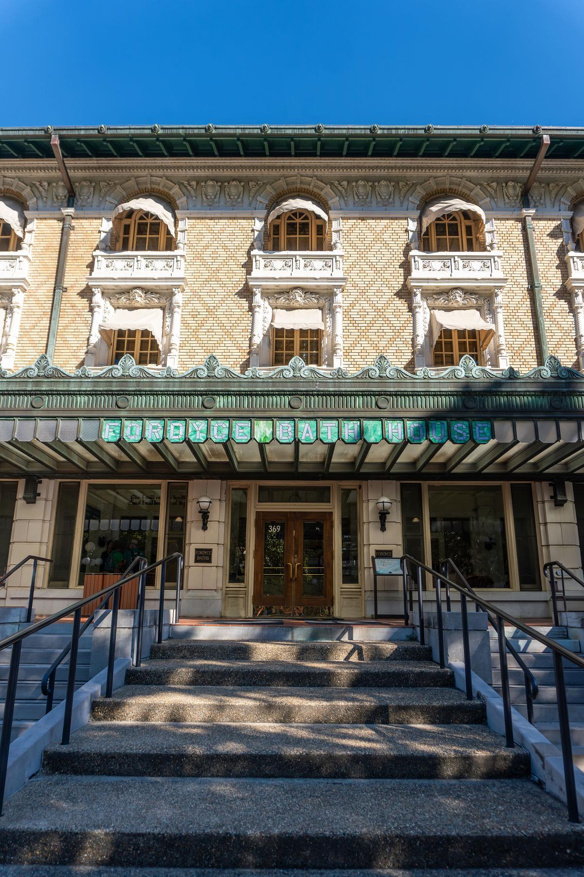 Stained glass spelling the words “Fordyce Bath House” hangs prominently from a copper marquee that showcases medallion designs and is topped with a repeating pattern of ornamental finials. The frieze designs around the windows display water-related motifs such as shells, starfish, dolphins, mermaids, and aquatic birds. Additionally, over some windows there is a frieze sculpture of the head of Neptune, god of the sea. (EWY Media/Shutterstock)