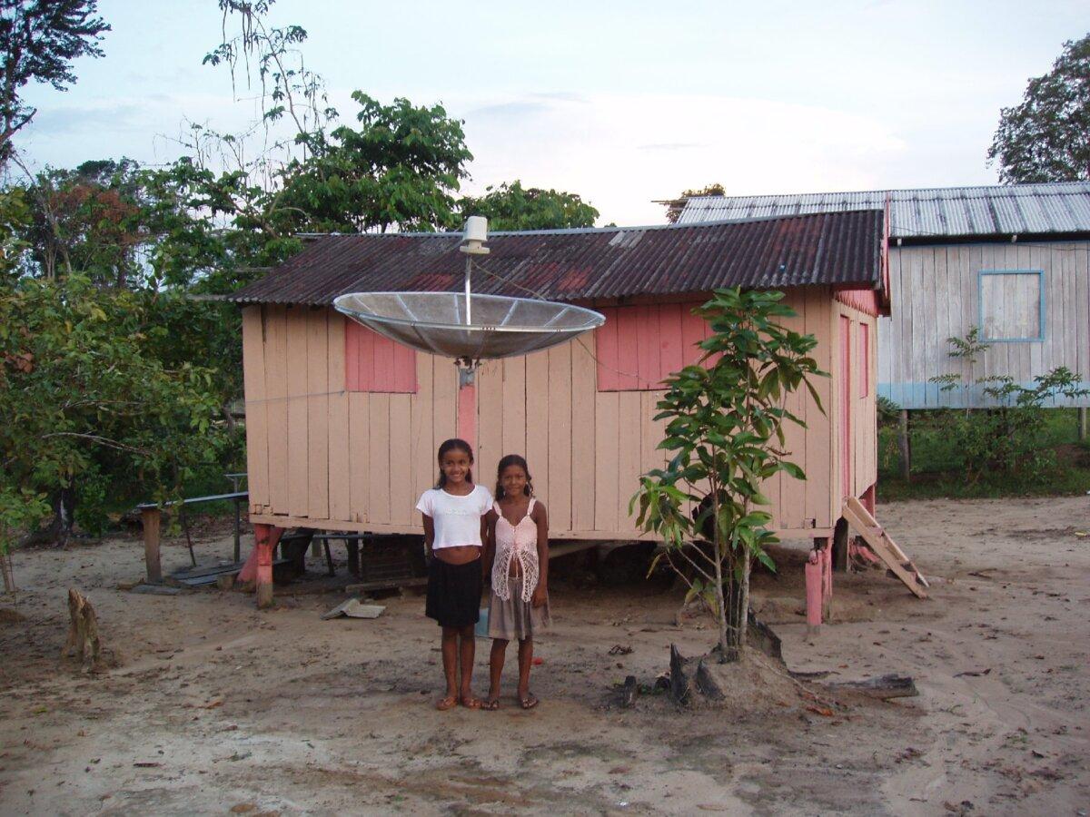 Children wave from in front of their home to passengers in a vessel on the Amazon River. (Photo courtesy of Victor Block)