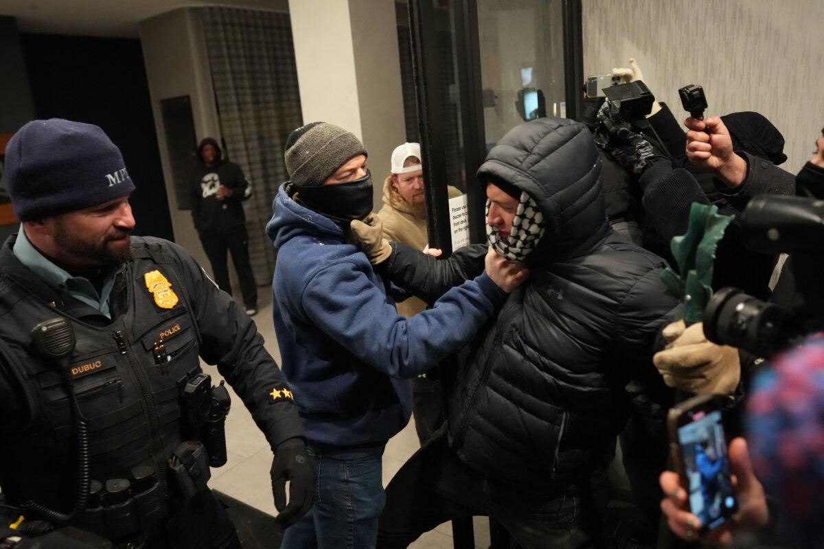A man next to a police officer grabs a protester during a demonstration against federal immigration enforcement operations in Minneapolis on Jan. 25, 2026. (Adam Gray/AP Photo)