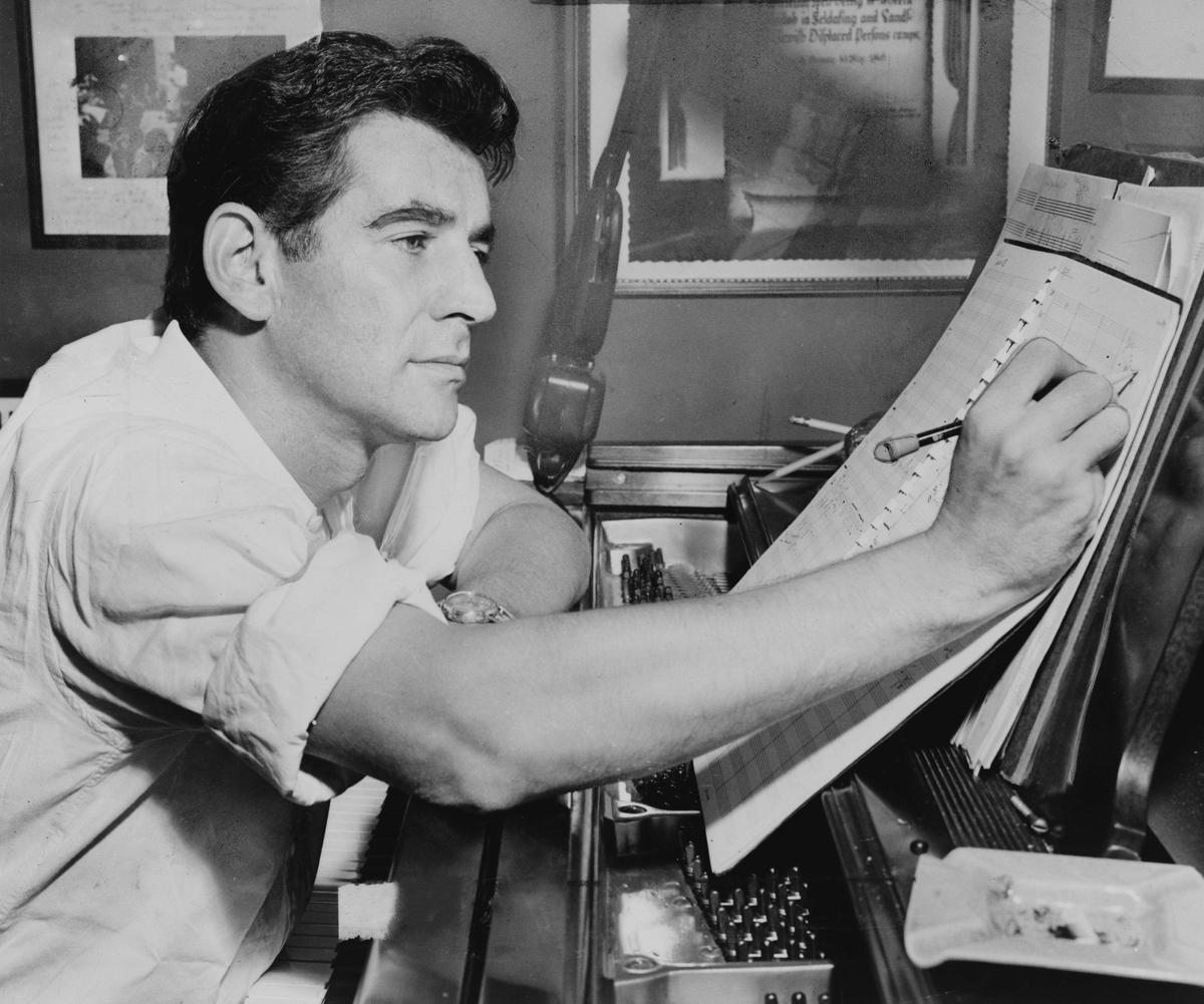 Leonard Bernstein seated at piano, making annotations to a musical score, 1955. Library of Congress. (Public Domain)
