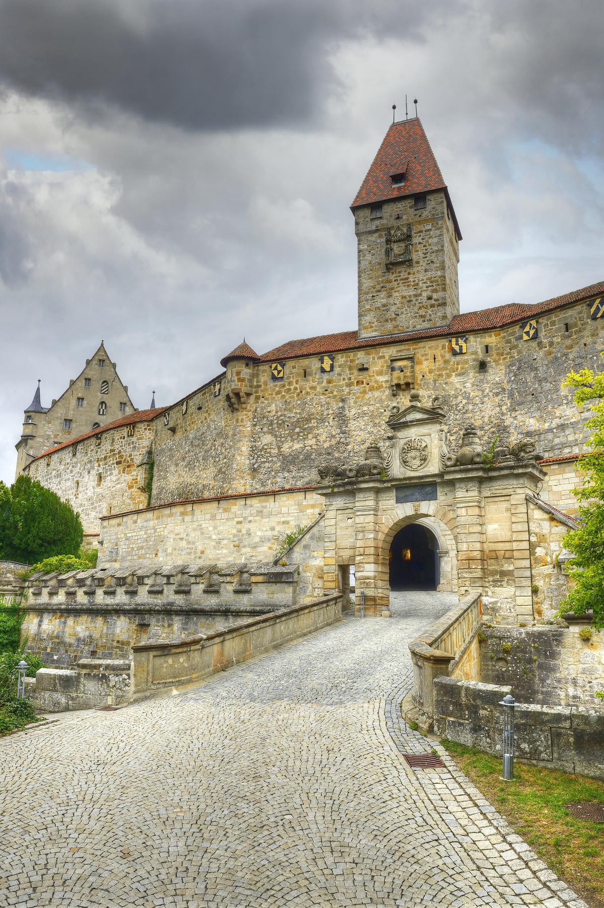 The tower entrance and bridge, where the main drawbridge was once located, are constructed of a vast quantity of stones. Visitors must pass through a triumphal arch decorated with ornate baroque-style sculptures representing military accoutrements such as cannon balls, and lions, which denote strength and divine protection. These flank a classical pediment sporting a crest. To the left of the entrance is one of Veste Coburg’s original structures, which formerly housed its arsenal. (Pecold/Shutterstock)