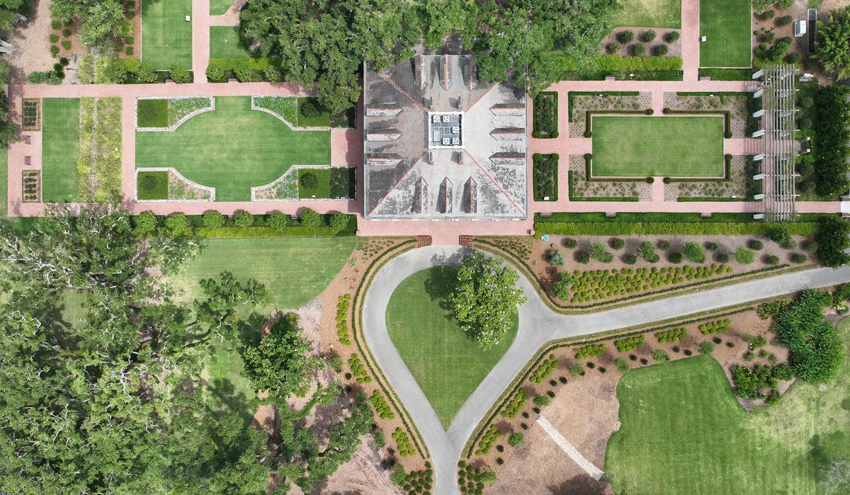 Sprawling symmetrical gardens on either side of the mansion include manicured lawns, mature trees, and flower gardens. From an aerial view, the mansion’s symmetry is evident, with three gabled dormer windows on each side of the square design. (Oak Alley Foundation)