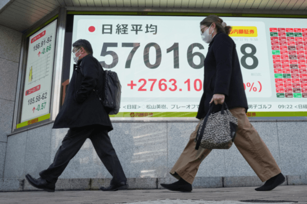 People walk past an electronic stock board displaying Japan's Nikkei index, at a securities firm in Tokyo on Feb. 9, 2026. (Eugene Hoshiko/AP)