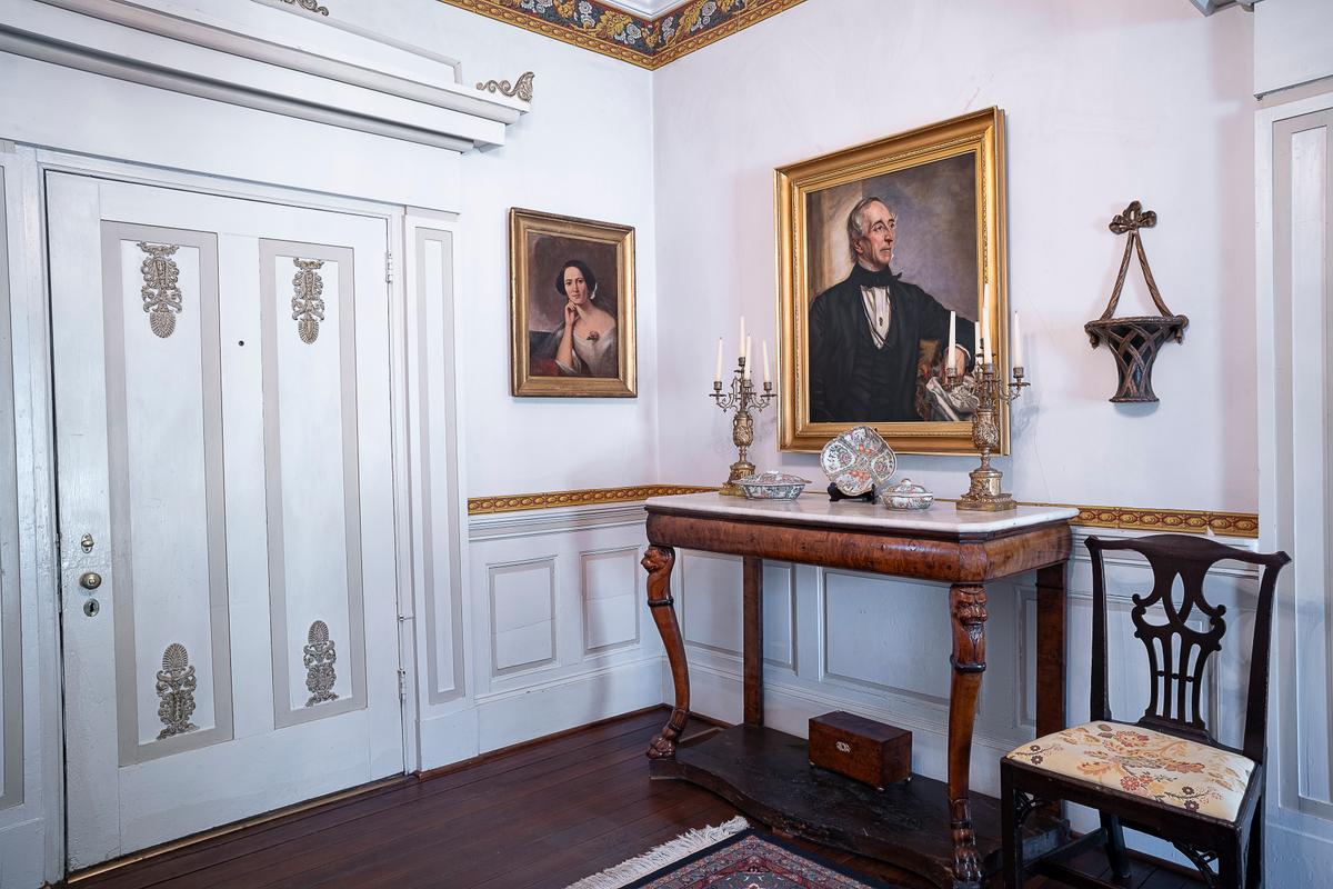 A copy of John Tyler's 1859 portrait by artist George Peter Alexander Healy (1813–1894) hangs in the house’s entryway; the original painting is housed at the National Portrait Gallery in Washington. The smaller painting is of a relative of John Tyler: Jane Cary Harrison Ruffin. The wide, painted front door is dressed with a Greek Revival-style applique inspired by a 19th-century design book by architect Minard Lefever (1798–1854). “Those are Julia Gardiner Tyler’s touches she added to the house,” said executive director Annique Dunning. Along the paneled chair railing is a hexagon-patterned wallpaper trim. (Sherwood Forest Plantation Foundation)
