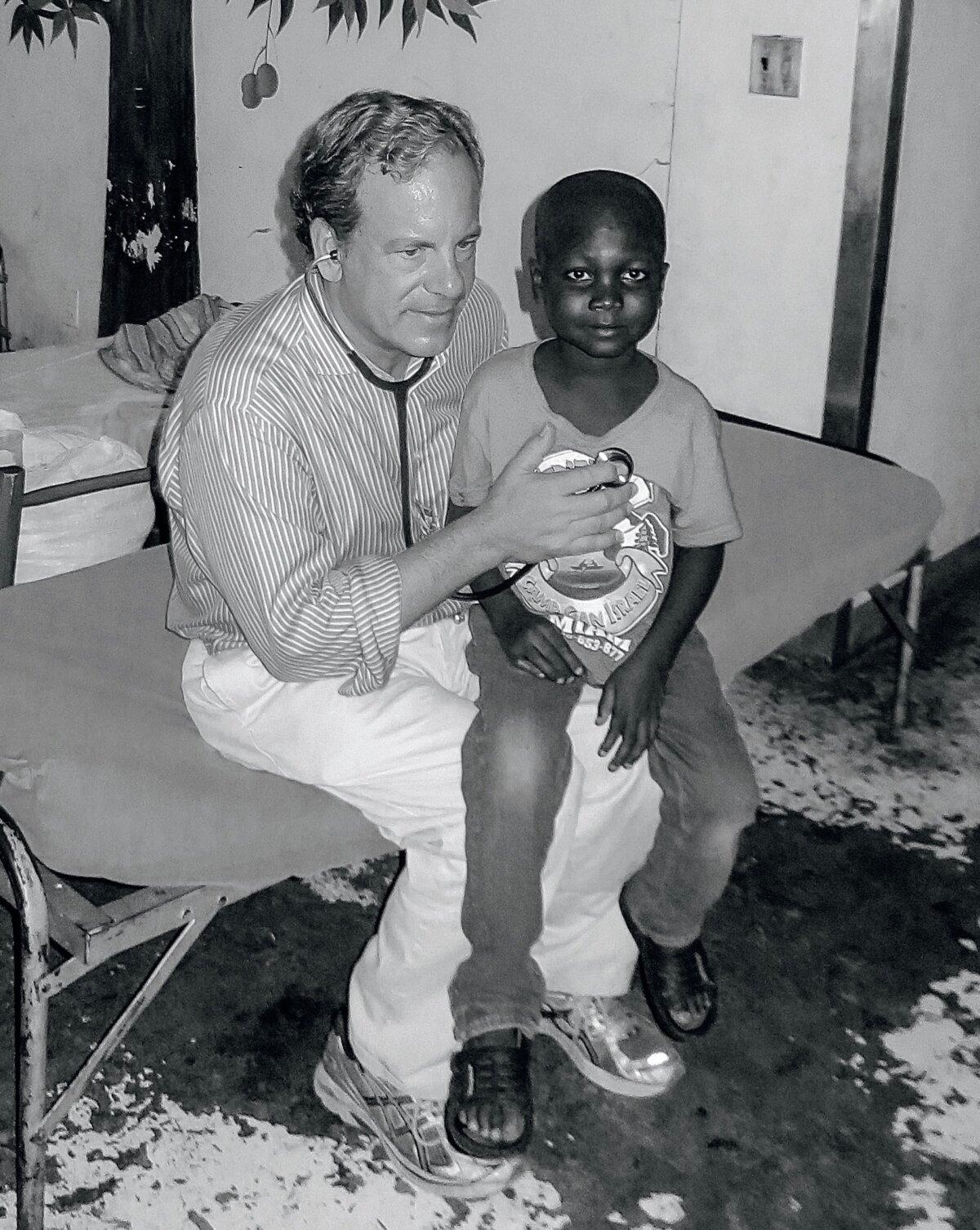Crandall treating and praying for a young boy in Haiti. He fully recovered from a parasitic illness. (Courtesy of Dr. Chauncey Crandall)