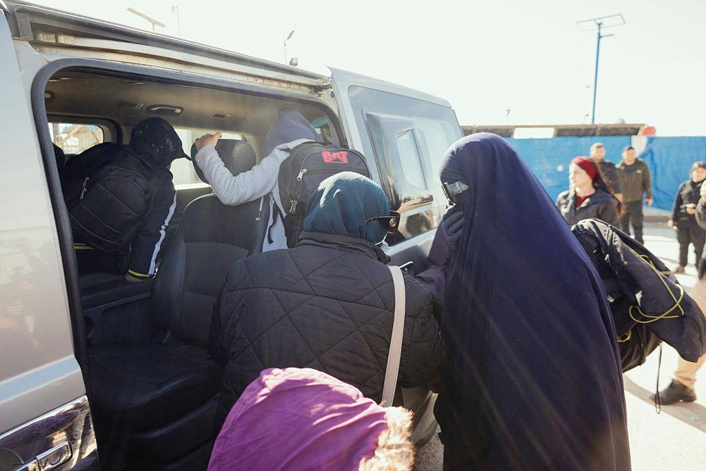 Australian families affiliated with ISIS walk beside a van with their belongings for departure at the Roj camp in al Malikiyah, Syria, on Feb. 15, 2026. (Amjad Kurdo/Middle East Images/AFP via Getty Images)