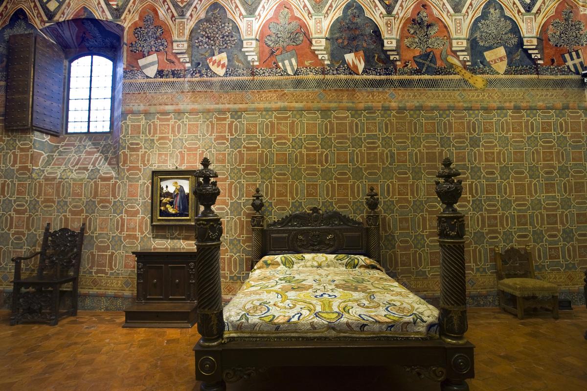 The first-floor bedroom, also known as the Peacock Chamber, was actually more than a bedroom. Here, the lady of the house would spend her day doing handworks, caring for her children, and receiving guests. Adorned with intricate murals featuring heraldic coats of arms and alternating geometric panels featuring motifs of crowns and lions, the room holds a bed from the 16th century, as well as window glass, which would not have been added before that time. (OfTheVillage/Shutterstock)