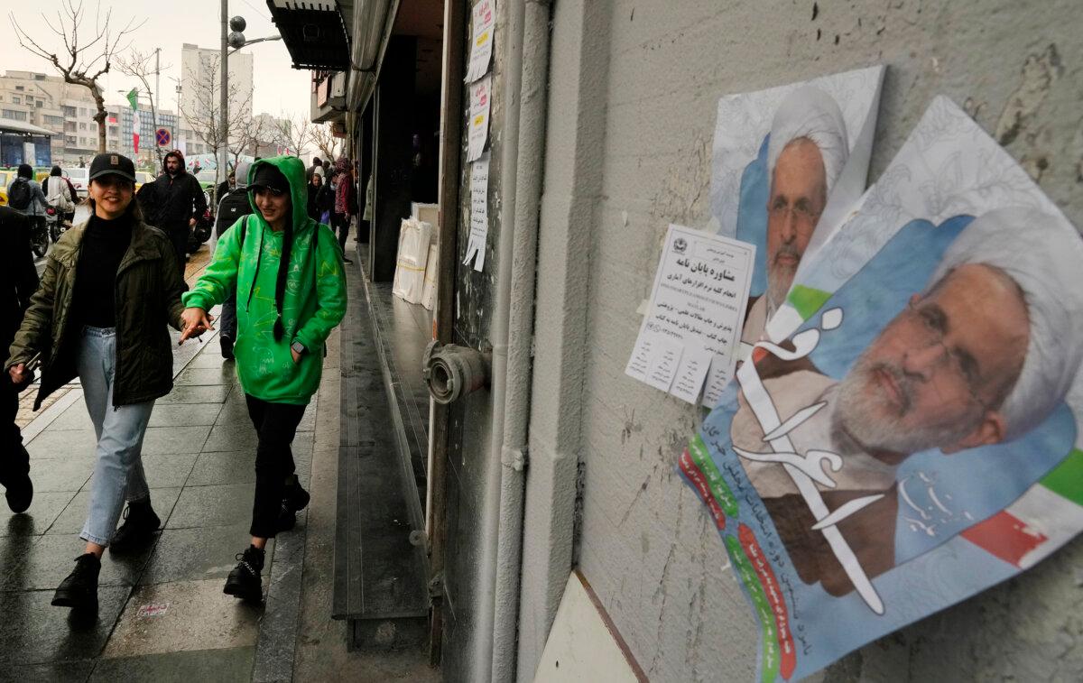 Women walk past electoral posters of Alireza Arafi, a candidate for the upcoming Assembly of Experts state-vetted elections, in Tehran, Iran, on Feb. 21, 2024. (AP Photo/Vahid Salemi)
