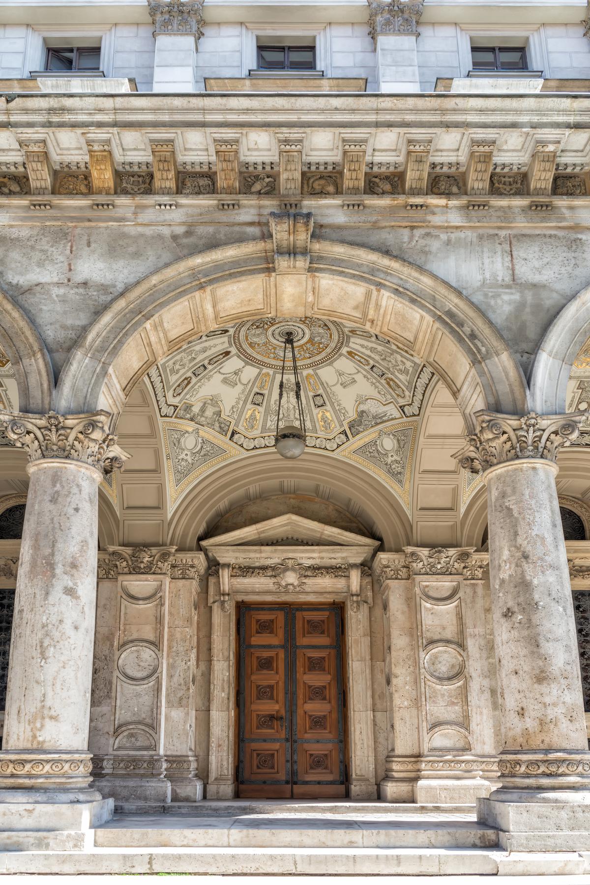 Symmetry is apparent no matter where one looks at the Hungarian State Opera House. This heavily carved, European oak-paneled doorway under a classic pediment and arch is proportionally centered between two capital-topped pilasters with circle and half-circle designs. These elements are positioned exactly between two limestone columns capped with Corinthian capitals and encircled at their bases with a masonry rope and rosette trim. The dome ceiling’s interior is embellished with colorful majolica (Italian earthenware) decoration, which contrasts with the precisely positioned paneled arches. (Claude Huot/Shutterstock)
